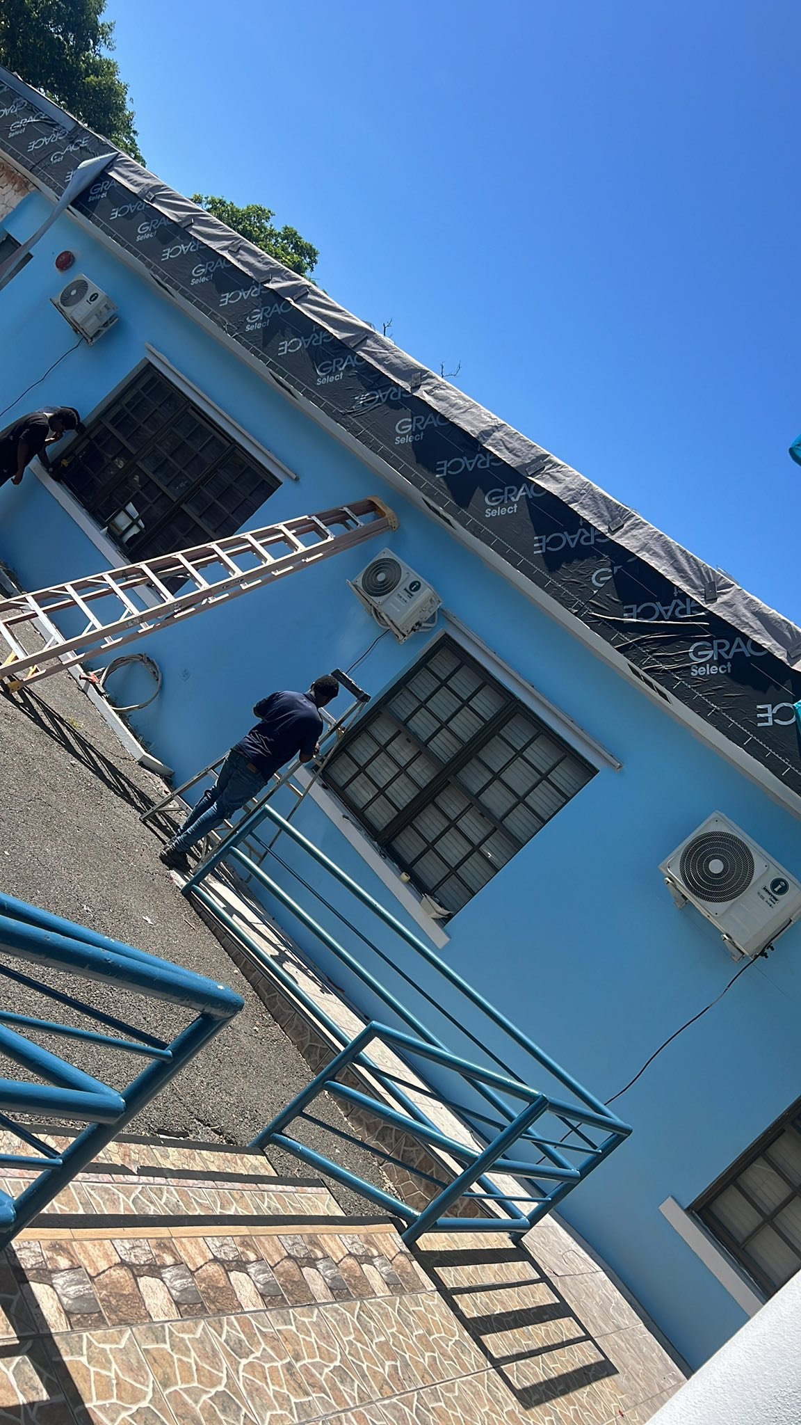 Two technicians installing multiple outdoor AC units on a building exterior