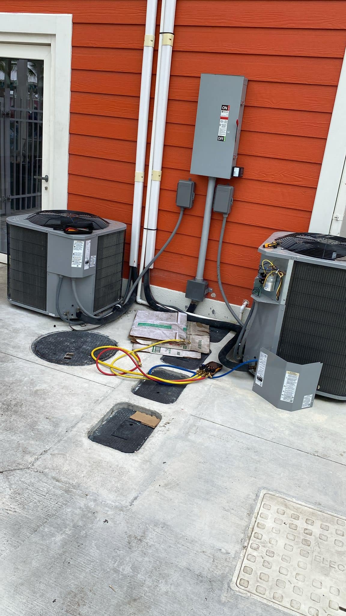Two large AC condensing units installed side by side outside a commercial property
